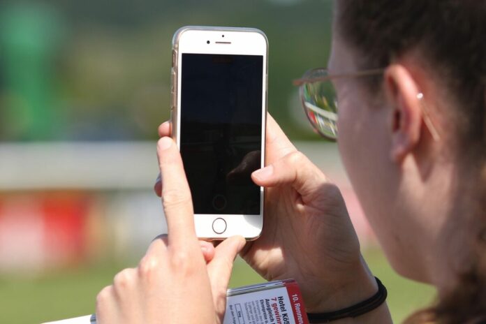 Ein Pferd wird mit dem iPhone im Absattelring fotografiert Handy